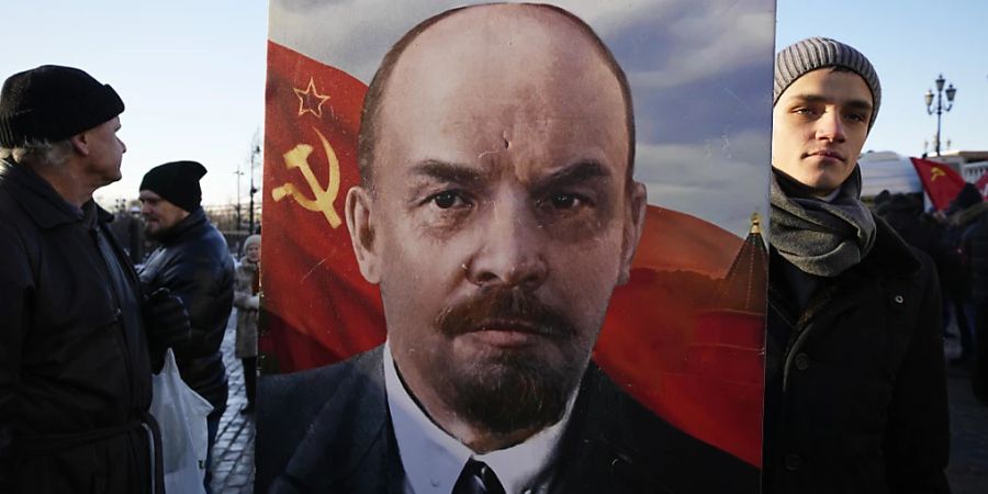Russische kommunistische Anhänger tragen ein Porträt von Wladimir Lenin, während sie auf dem Roten Platz in Moskau Blumen am Mausoleum des Sowjetgründers Wladimir Lenin niederlegen, um dessen 100. Todestag zu feiern. Foto: Alexander Zemlianichenko/AP/dpa