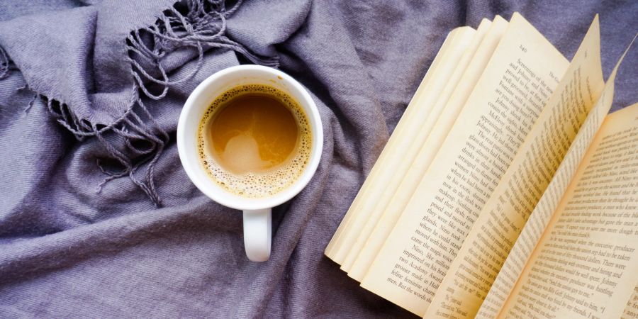 offenes buch neben kaffee-tasse