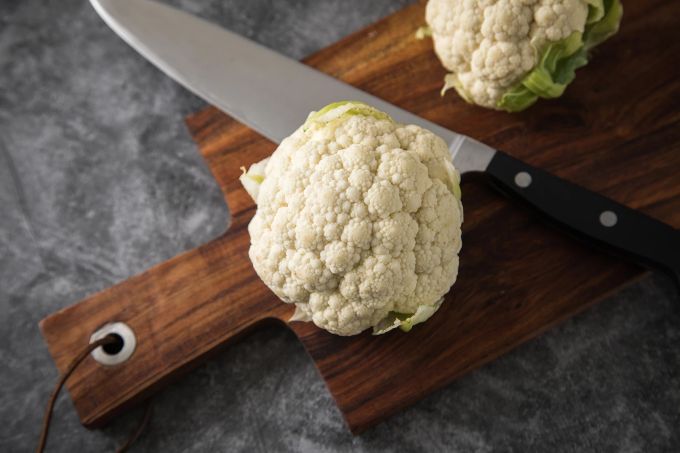 Blumenkohl kann man auch roh essen: zum Beispiel als Zutat in Smoothies oder geraspelt im Salat. Schneidebrett Blumenkohl Rohkost Messer
