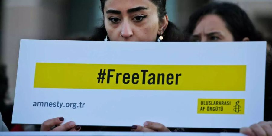 Eine Frau protestiert gegen die Inhaftierung des Amnesty-Ehrenvorsitzende Taner Kilic. Sie hält ein Schild mit dem Text «#befreitTaner» vor ihre Brust.
