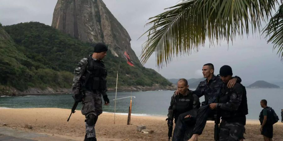 Brasilianische Polizisten tragen einen Kollegen, der sich bei der Suchaktion nach einer Schiesserei unter dem Zuckerhut von Rio de Janeiro (BRA) verletzt hat