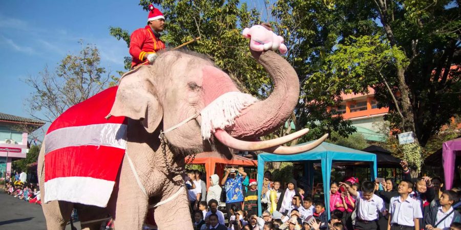 Der Weihnachtsmann in Thailand reitet einen Elefanten.