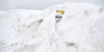 Ein Haltestellenschild ist in Österreich zwischen Schneemassen.