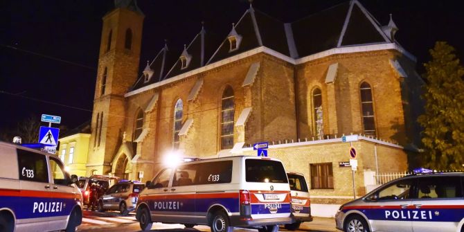 Polizeiautos stehen vor der Wiener Kirche.