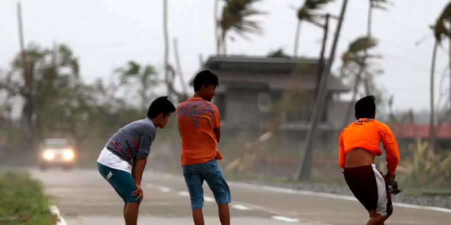 Philippinische Dorfbewohner werden von der Windstärke des Taifuns beinahe mitgerissen.