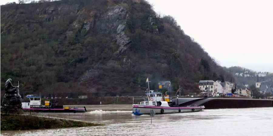 Zwei Schlepper fahren auf dem Rhein bei St. Goarshausen vor einem gekenterten Tankschiff (r.), links im Bild steht die Loreley-Statue.