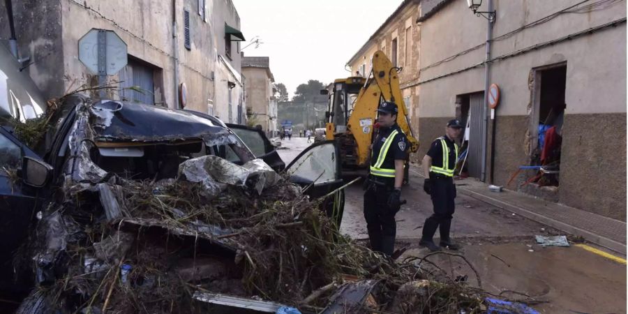 Zwei lokale Polizisten bei einem vom Unwetter zerstörten Auto in Sant Llorenc auf Mallorca.