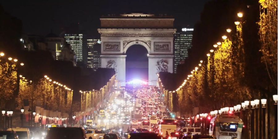 Hell beleuchtet ist die Champs-Élysées mit dem Arc de Triomphe im Hintergrund am Abend in der Saine-Metropole.