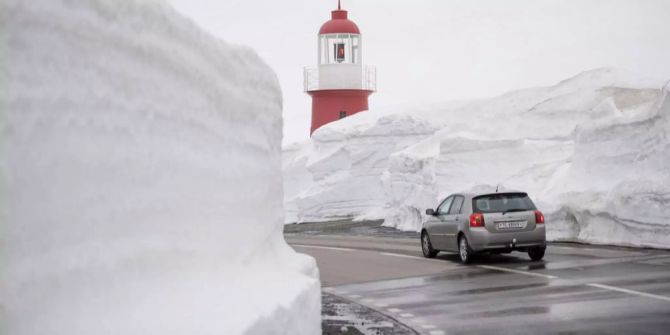 Die ersten Autos ueberqueren den am Freitag 27. April 2018 geoeffneten und noch mit hohen Schneewaenden bedeckten Oberalppass zwischen Andermatt und Sedrun.