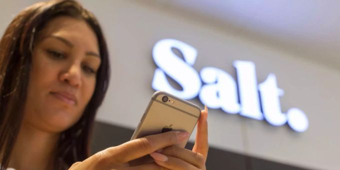 Salt hat mehr Kunden. Eine Verkäuferin benutzt ein Smartphone in der Salt Filiale.