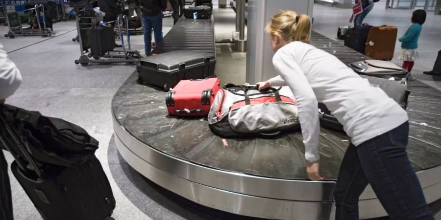 Eine Passagierin nimmt ihre Tasche vom Gepäckband in der Ankunft 2 im Flughafen Zürich.