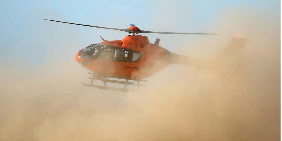 Ein Rettungshubschrauber startet am Rande des Hambacher Forstes in einer Staunbwolke.