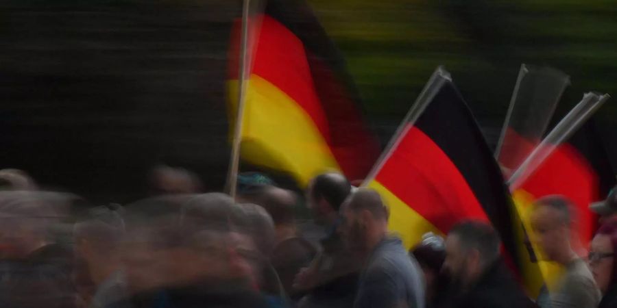 Mit Deutschland-Fahnen ziehen Demonstrationsteilnehmer durch die Innenstadt von Chemnitz.