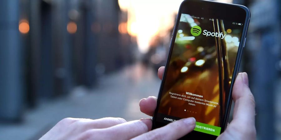 Eine Person registriert sich in der Spotify-App auf seinem iPhone 6 in einer Berliner Strasse.