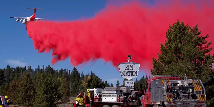 Ein Flugzeug verteilt ein brandhemmendes Mittel über einem Wald bei Bondurant in Wyoming (USA).