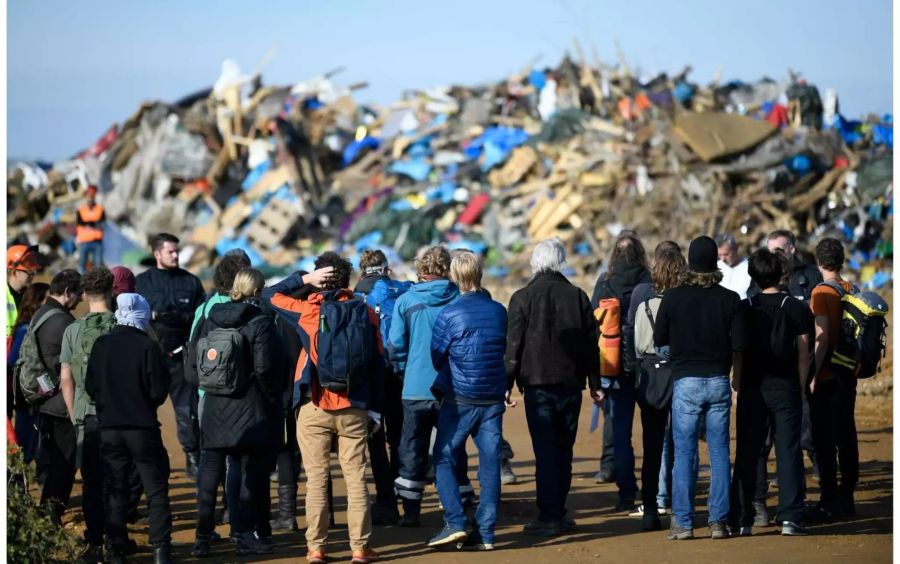 Aktivisten stehen am Hambacher Forst auf dem Geländer der RWE vor einer Ansammlung von Gegenständen. Dort werden die Sachen gelagert, die bei der Räumung der Camps in den vergangenen Wochen beschlagnahmt wurden.