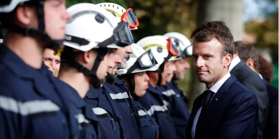 Der französische Präsident Emmanuel Macron (r.) schüttelt die Hände der Feuerwehrmänner während seines Besuchs bei den Opfer der Überschwemmungskatastrophe in Villalier (F).