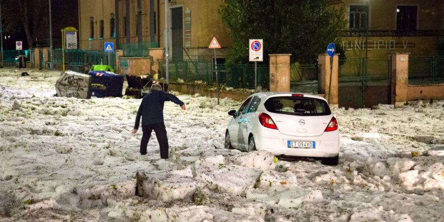 Ein Mann versucht auf diesem am 22.10.2018 zur Verfügung gestellten Foto ein durch Hagelmassen blockiertes Auto zu erreichen, nachdem ein Hagelsturm Rom heimgesucht hatte.