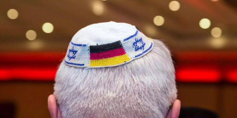 Ein Mann trägt eine Kippa mit eingearbeiteten israelischen und deutschen Fahnen.