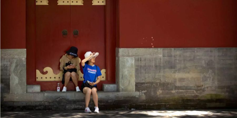 Zwei Frauen sitzen vor der Tür eines Gebäudes in Peking.