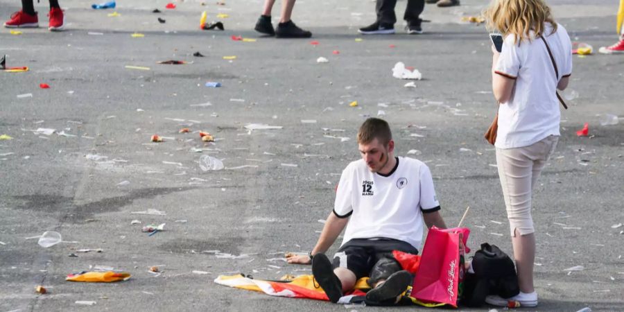 Ein Fussballfan sitzt nach dem Ausscheiden der Deutsche Fussball Nationalmannschaft am Boden.