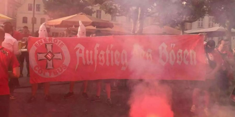 Mit Masken und dem Transparent «Aufstieg des Bösen» zeigen sich Cottbus-Anhänger nach dem Aufstieg.