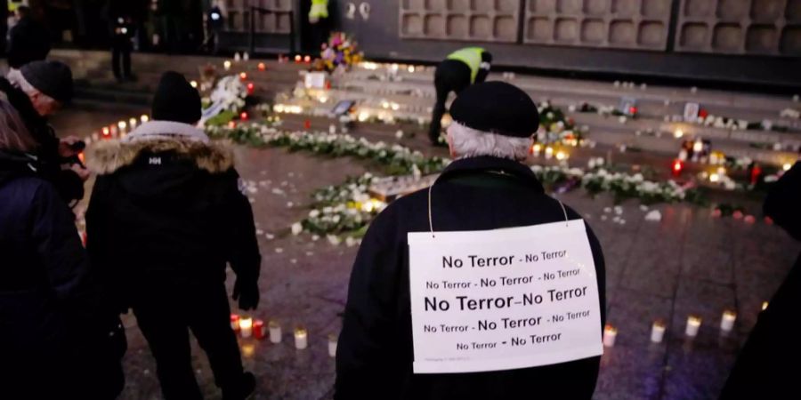 Ein Mann steht vor dem Mahnmal in Berlin und fordert das Ende des Terrors.