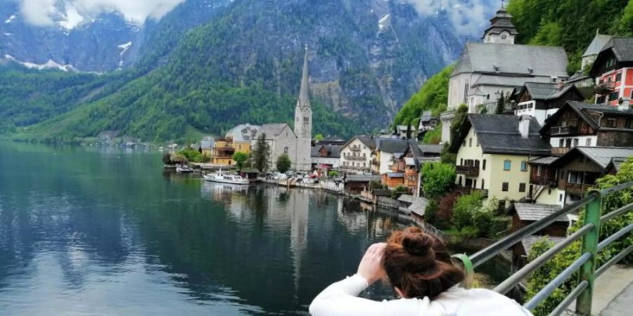 Eine Touristin fotografiert den Hallstätter See in Österreich. Foto: Matthias Röder/dpa