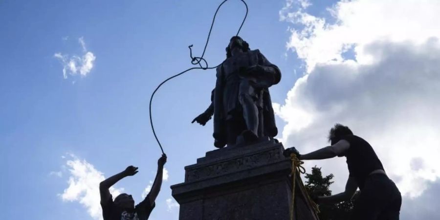 Zwei Männer befestigen ein Seil um den Hals einer Statue von Christopher Columbus. Foto: Evan Frost/Minnesota Public Radio/AP/dpa