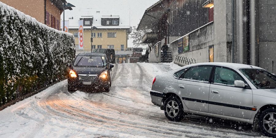 Mit Schnee bedeckte Quartierstrasse in Belp und fahrende Autos. - Kanton Bern