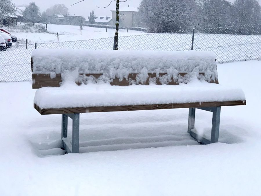 In Schmitten FR ist eine Parkbank zentimeterdick mit Schnee bedeckt.