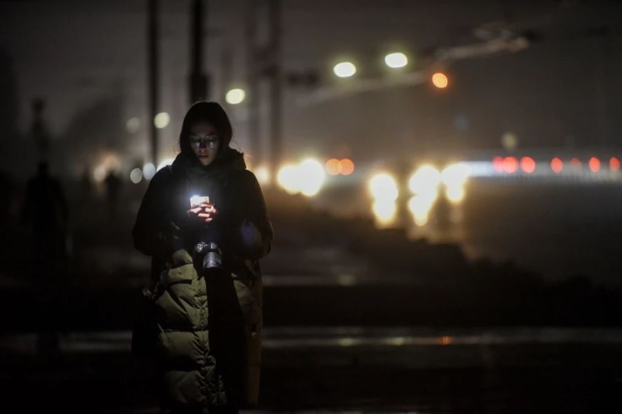 Eine Frau nutzt in Kiew ihr Handy, um die Strasse zu beleuchten.