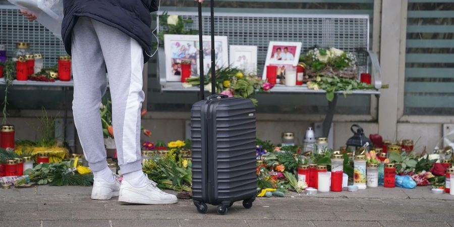 Eine Reisende schaut sich die Blumen, Kerzen und verschiedene Bilder im Wartehäuschen am Bahnhof zum Gedenken an die Opfer der Messerattacke an.