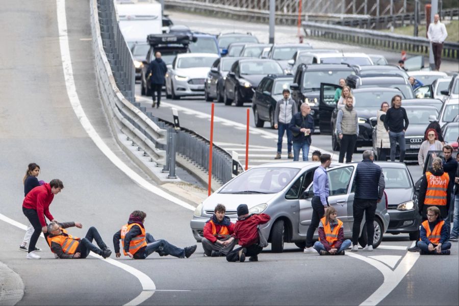 Reisende versuchen, die nicht angeklebten Protestierenden von der Strasse zu tragen.