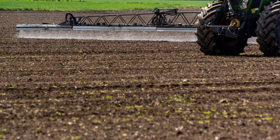 Ein Traktor bringt auf einem Acker Pflanzenschutzmittel aus.