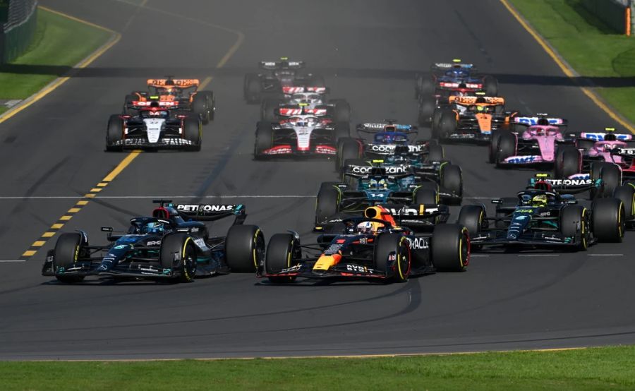 George Russell im Mercedes (l) zieht in der ersten Kurve an Max Verstappen im Red Bull (m) vorbei.