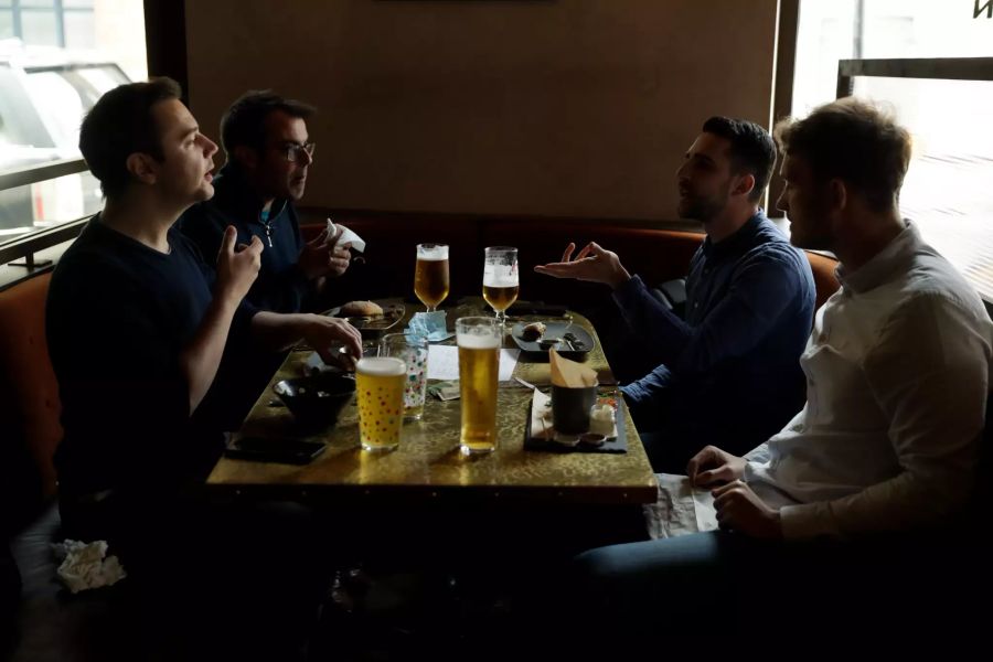 Menschen sitzen im Pub «The Gun» zusammen an einem Tisch.