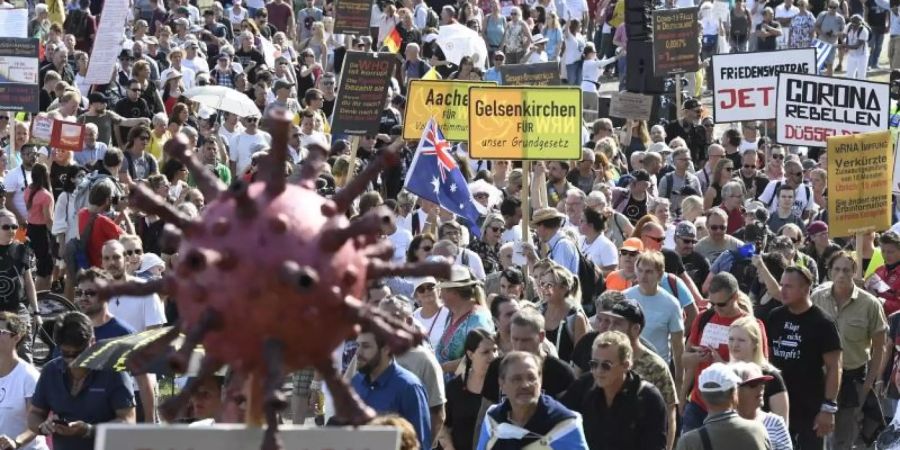 Teilnehmer einer Demonstration protestieren mit Schildern auf den Rheinwiesen gegen die Massnahmen zur Bekämpfung des Coronavirus. Foto: Roberto Pfeil/dpa