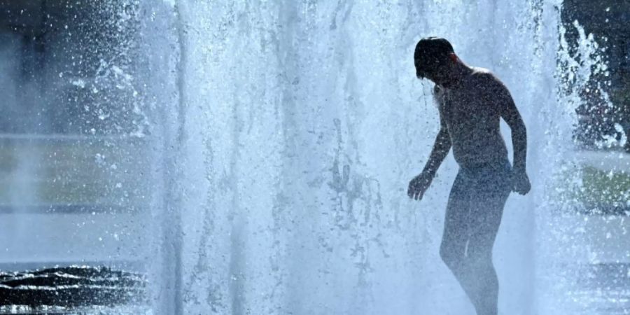 Ein Junge kühlt sich in einem Springbrunnen ab