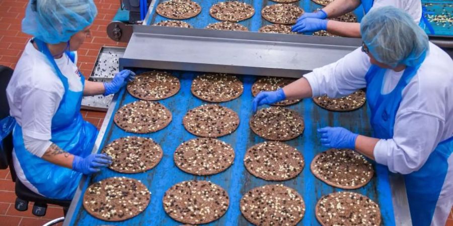 Mitarbeiterinnen belegen im Pizzawerk der Firma Dr. Oetker kakaohaltige Pizzaböden mit Schokoladensplittern. Die Schokoladenpizza wird nach zwei Jahren eingestellt. Foto: Jens Büttner/dpa-Zentralbild/dpa