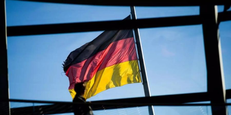 Vor der Kuppel des Reichstaggebäudes weht die Deutschlandfahne. In einem internationalen Ranking zum Wohlbefinden der Bevölkerung schneidet Deutschland gut ab. Foto: Gregor Fischer/dpa