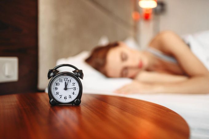 Egal ob Smartphone oder klassisch: Weit weg ist immer ein guter Platz für den Wecker. Wecker Tisch Holz Frau Bett