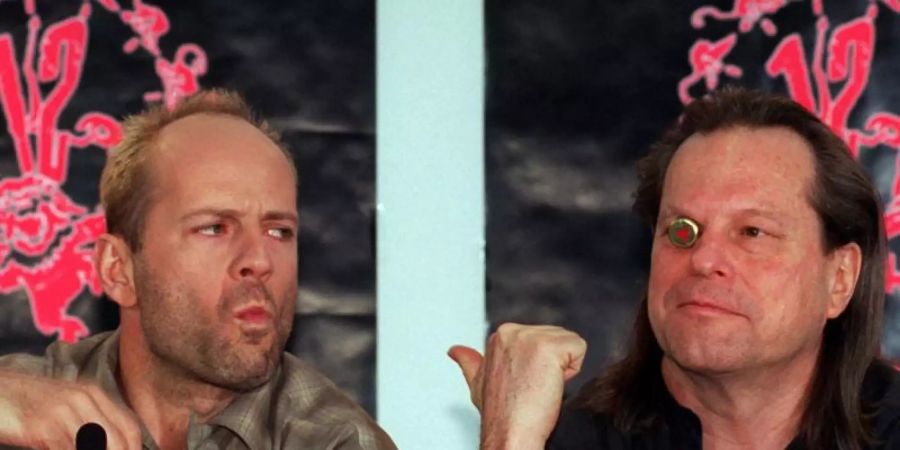 Regisseur Terry Gilliam (r) neben Schauspieler Bruce Willis 1996 auf der Berlinale bei der Vorstellung ihres Films "12 Monkeys". Foto: Andreas Altwein/dpa