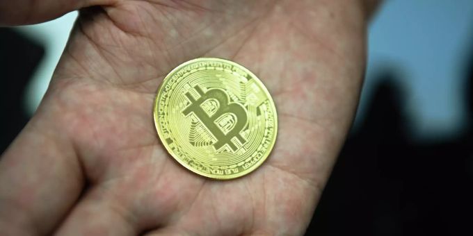 Ein Mann hält eine nachgemachte Münze mit dem Bitcoin-Logo in den Händen. Bitcoin steigt erstmals über 25 000 US-Dollar