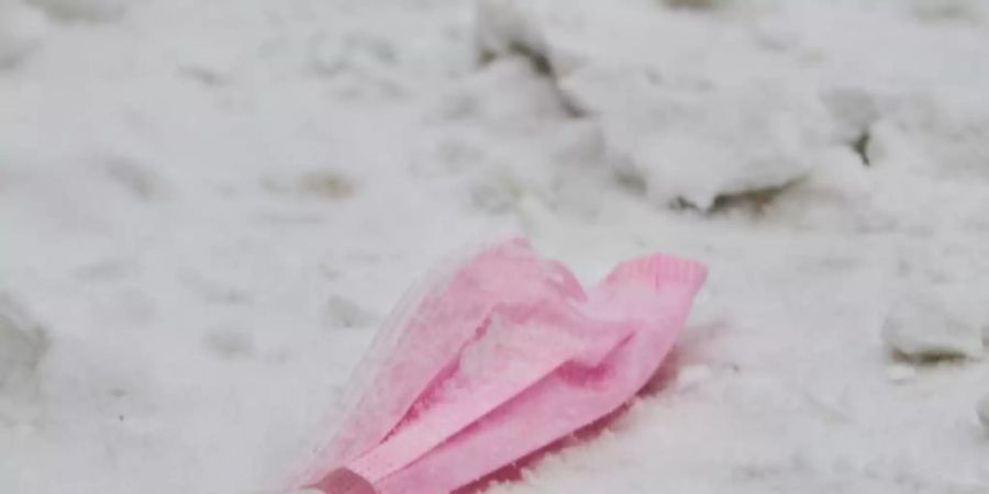 Dieser Mund-Nasen-Schutz hat ausgedient: Eine pinke Maske im Schnee. Foto: Annette Riedl/dpa/Symbolbild/Archiv