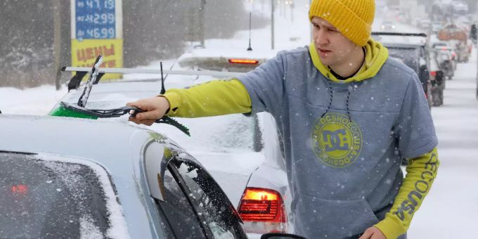 Ein Mann wischt bei Schneefall Schnee von einem Auto auf der Dmitrovskoye-Autobahn. Nach stundenlangen starken Schneefällen und -stürmen steuert die russische Hauptstadt Moskau auf eine Rekordschneedecke zu Winterwetter in Russland