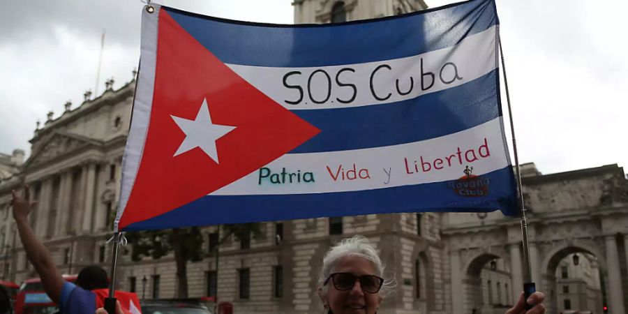 Ein Mann hält eine Fahne in den Farben der kubanischen Nationalflagge mit der Aufschrift «S.O.S Cuba, Patria Vida y Libertad» (S.O.S Kuba, Vaterland, Leben und Freiheit) bei einem Protest im Zentrum Londons. Menschen protestierten, um ihre Solidarität mit den Regierungsgegnern in Kuba zu bekunden. Foto: Tayfun Salci/ZUMA Press Wire/dpa