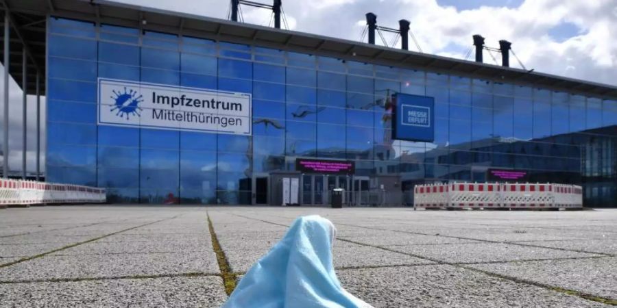 Eine Maske liegt vor dem Impfzentrum in der Messe Erfurt. In den ostdeutschen Bundesländern sind weniger Menschen gegen Covid-19 geimpft als bundesweit. Foto: Martin Schutt/dpa-Zentralbild/dpa
