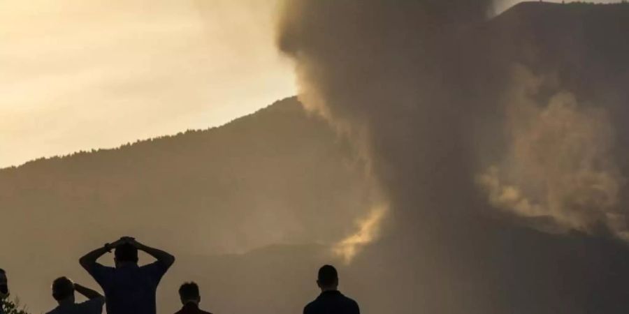 Anwohner blicken von einem Hügel aus auf die Lava, die weiterhin aus dem Vulkan auf der Insel La Palma fliesst. Foto: Emilio Morenatti/AP/dpa