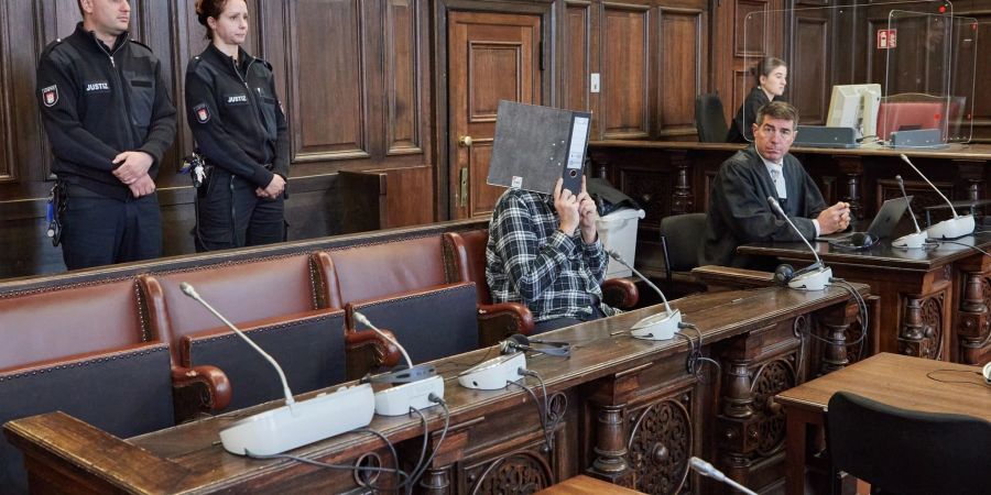 Der Angeklagte (mit Ordner vor dem Gesicht) sitzt im Gerichtssaal neben seinem Anwalt Robert A. Funk (r) kurz vor der Urteilsverkündung.